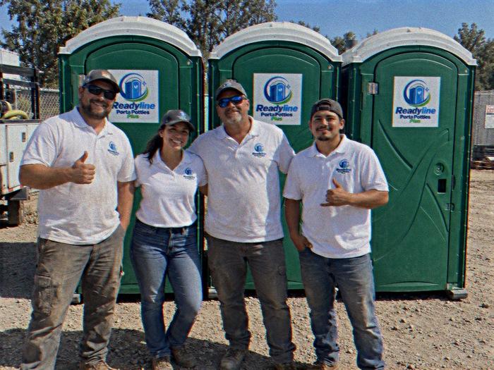 Readyline Porta Potties Plus crew in white polo shirts beside three green porta potties in Raleigh